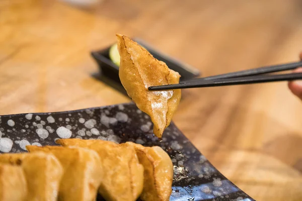 Κοντινό Chopstick Κρατώντας Ένα Κομμάτι Gyoza Dumpling Από Την Πλάκα — Φωτογραφία Αρχείου