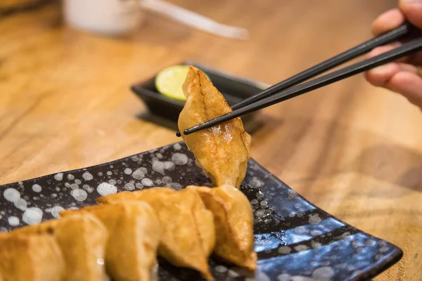 从组合板上拿块饺子或饺子把筷子合起来 — 图库照片