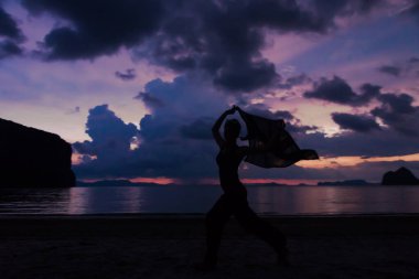 Gölgeli kadın Alacakaranlık gökyüzü ile koşuyor. Arka planda kumsalda renkli ve bulutlu.