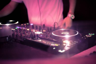 DJ gece kulübünde biraz müzik ve kumanda karıştırıyor.