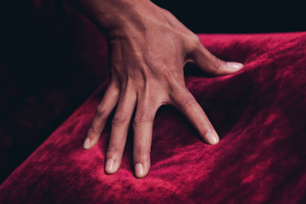 Black skin hand touching the red carpet fur on a chair make some bright red light
