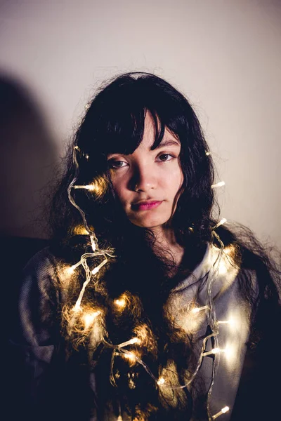 curly hair lady hang led light bulb on her head look at camera