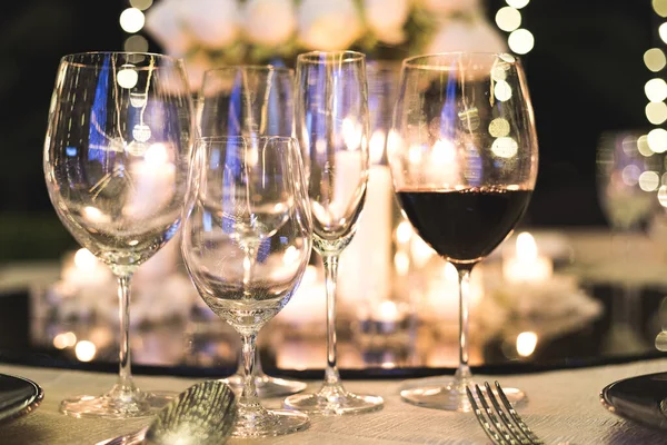Wine glass cup on dinner table with one that have wine inside on blurred background