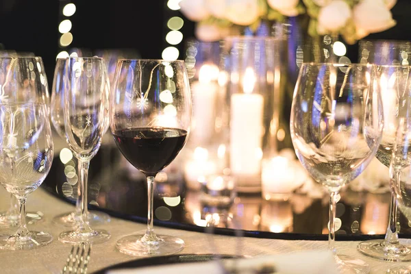 Wine glass cup on dinner table with one that have wine inside on blurred background