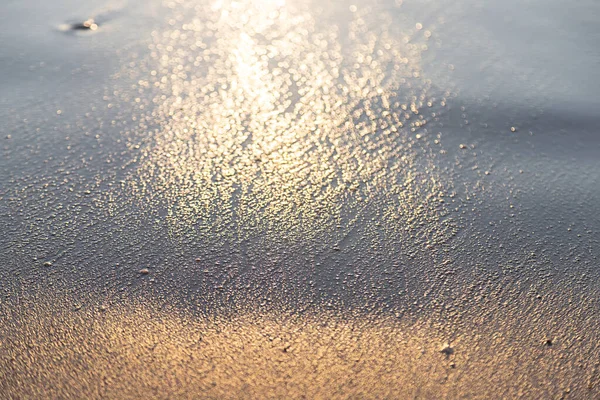 Black sand texture surface on the beach, sunset light reflection make golden. Water and sand mix with mineral ore and Crude oil