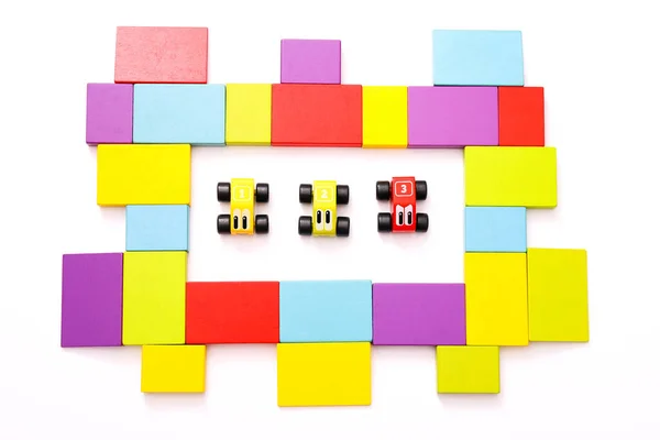 Jouets éducatifs pour enfants. Voitures en bois colorées avec des numéros et le cadre de blocs colorés autour sur fond blanc. Vue du dessus — Photo