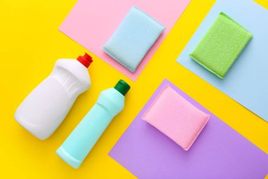 Mutfakta sarı arka planda farklı yüzeyler için renkli temizlik seti. Üst manzara, düz uzanma