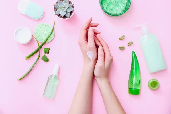 Manos de mujer con crema. Productos cosméticos naturales sobre fondo rosa, vista superior — Foto de Stock