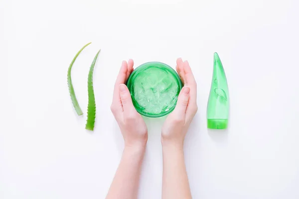 Woman hands holding aloe gel. Aloe vera leaves and cosmetic products on white surface. Top view — Stock Photo, Image