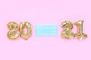 Folyo balonları 2021 numaralı formda pembe arka planda koruma maskesi, üst manzara. Yeni normal kutlama Yeni yıl konsepti.