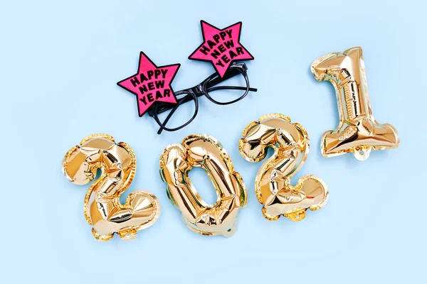 Balony foliowe w postaci cyfr 2021 i świąteczne okulary na niebieskim tle. Dekoracje noworoczne. Widok z góry — Zdjęcie stockowe