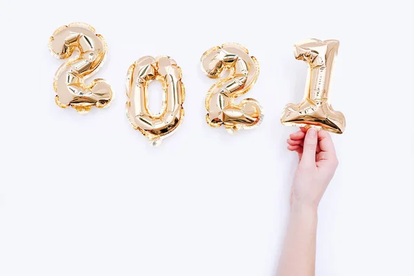 Balony foliowe w postaci cyfr 2021 i żeńska dłoń trzymająca numer jeden na białym tle. Święto Nowego Roku. — Zdjęcie stockowe