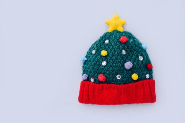 Gri arka planda Noel ağacı şeklinde bir kış şapkası. Asgari Noel konsepti. Üst görünüm