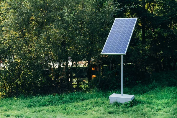 Batería solar en el fondo de los árboles. Fuentes de energía alternativas modernas respetuosas con el medio ambiente. — Foto de Stock