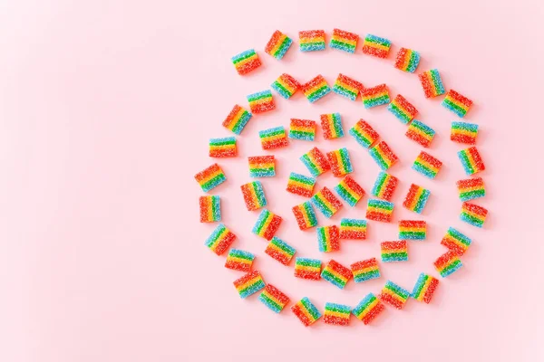 Form av färgglada virvel gjord av gelé godis på rosa bakgrund, ovanifrån — Stockfoto