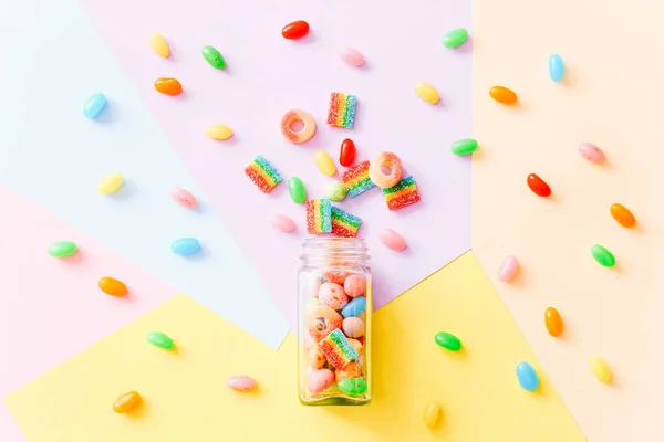 다채 로운 배경에 유리병에 흩어져 있는 화려 한 사탕들이 뒤섞여 있다. 위에서 본 풍경 — 스톡 사진
