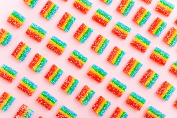 Arco iris jugosos caramelos gomosos fondo. Patrón de dulces de gelatina sobre fondo rosa — Foto de Stock