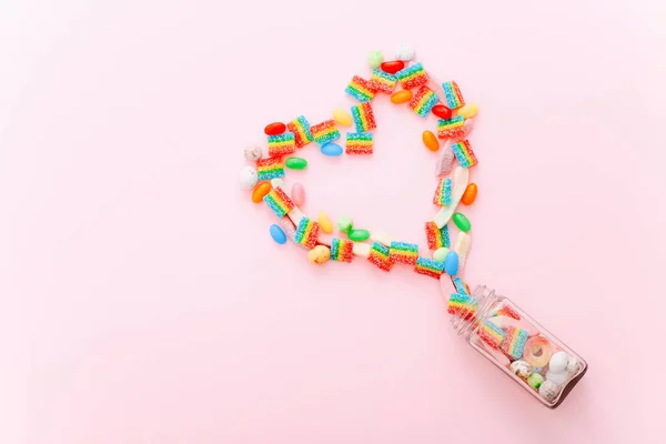 하트는 분홍색 배경에 다양 한 설탕 사탕으로 만들어 져 있습니다. 발렌틴 데이 컨셉이야. 맨 위 뷰, 평평 한 면. — 스톡 사진