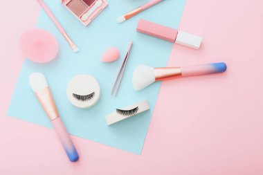 Mavi ve pembe arka planda makyaj malzemeleri ve aksesuarlar. Güzellik konsepti. Düz konum, üst görünüm