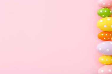 Pembe arka planda fotokopi alanı olan renkli plastik Paskalya yumurtaları. Üst görünüm