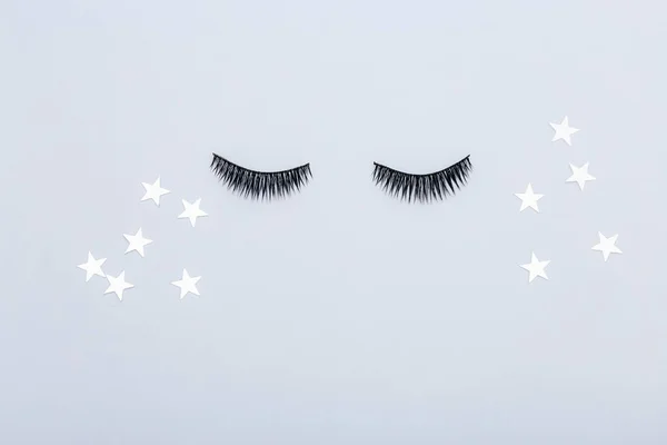 Artificial eyelashes for makeup and stars on a gray background. The view from the top.