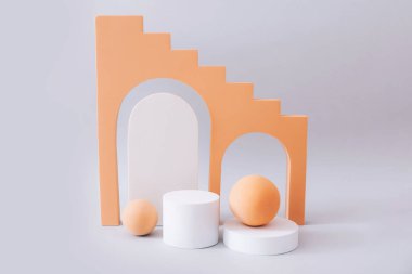 Geometrik şekiller, gri arkaplanda ürün gösterimi için podyumları şekillendirir. Ürün tanıtımını minimal biçimde temsil et.