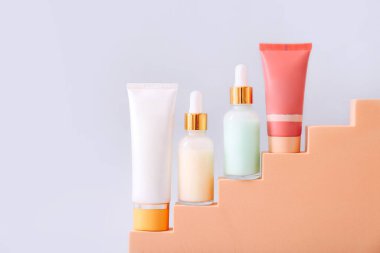 Gri arka planda geometrik podyumda kozmetik ürün sunumu. Güzellik ve vücut bakım ürünleri konsepti.