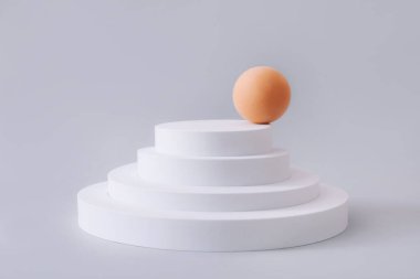 Geometrik şekiller, gri arkaplanda ürün gösterimi için podyumları şekillendirir. Ürün tanıtımını minimal biçimde temsil et.