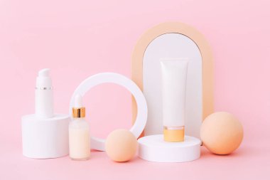 Geometrik podyumlarda kalan kozmetik cilt bakım ürünleri. Pembe arka planda ürün sunumu.