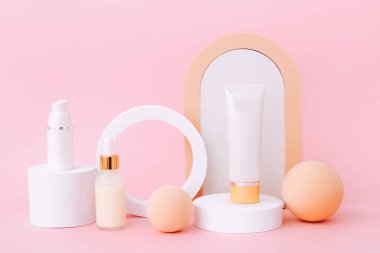 Geometrik podyumlarda kozmetik şişeler. Pembe arka plandaki doğal güzellik ürünleri için sunum şablonu