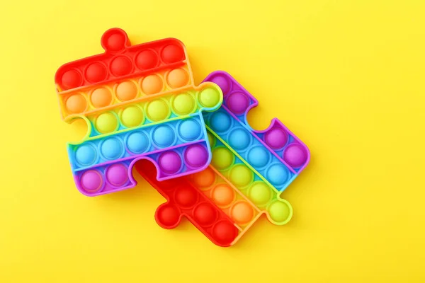 Zabawka Popit w formie łamigłówek na żółtym tle. Kolorowe Pop to zabawka — Zdjęcie stockowe