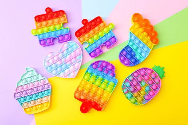 Kleurrijke Push Pop It Bubble Sensory Fidget Speelgoed van verschillende vormen, op kleurrijke achtergrond — Stockfoto