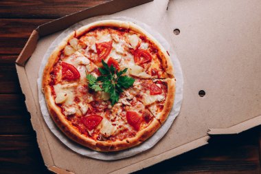 Koyu ahşap arka planda pizza kutusunda.