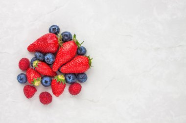 Hafif arkaplanda taze çilek ve yaban mersini, üst görünüm kopyalama alanı