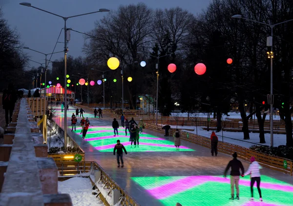 Άνθρωποι περνούν το βράδυ στο χρωματιστό παγοδρόμιο — Φωτογραφία Αρχείου