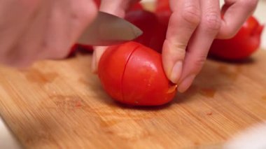 Kadının elleri mutfak bıçağı kullanarak tahta kesme tahtasıyla taze domates kesiyor. Kesilmiş domates..