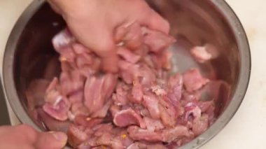 Kadın kıymayı mavi bir tabakta karıştırıyor. Elle karıştırma işlemi gösterilir. Yakın plan.
