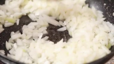 Soğanlar yağda kızartma tavasında kızartılır. Dilimlenmiş soğan karamelli tavada cızırdıyor ahşap kaşıkla karıştırılıyor.