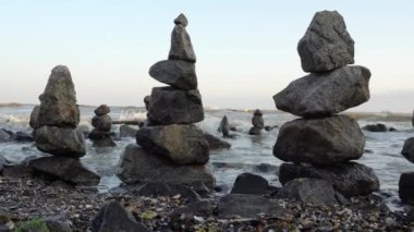 Güneşli bir günde kumsalda dengeli taş piramidi. Arka planda sakin deniz ve dalgalar yoktur. Deniz sahilinde Zen Taşları, meditasyon, spa, uyum, sakinlik, denge konsepti