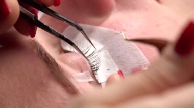 Uzun kıvrımlı kirpikli kadın gözü. Kirpik uzatma prosedüründen geçen genç kadın, yakın plan..