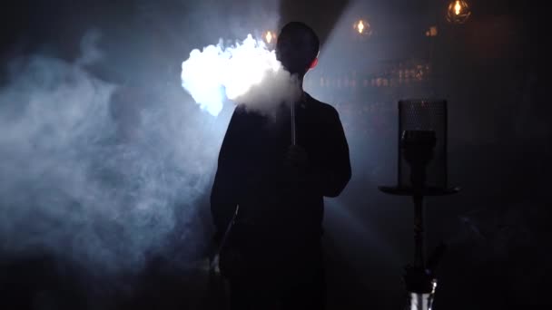 ชายสลูเอท สูบบุหรี่ในบาร์ สื่อ ผู้ชายสูบบุหรี่ที่บาร์ในที่มืดบนพื้นหลังของแสงสีฟ้า ไนท์บาร์กับฮูกาห์ — วีดีโอสต็อก
