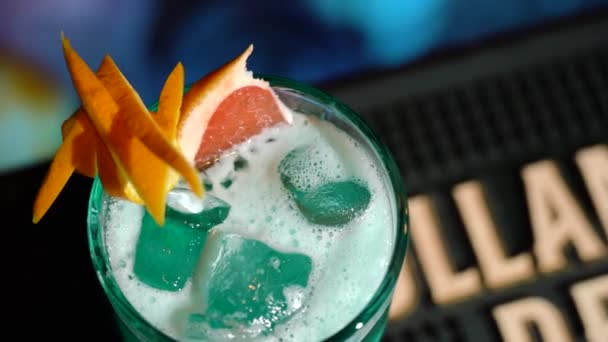 Zblízka pohled na sklenici zeleného koktejlu a barman přidání červené třešně na okraji. Makro záběr na sklenici tropického zeleného koktejlu plného ledu. — Stock video