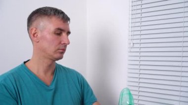 Erkek oksijen maskesi takar ve COVID-19 salgınından kendini izole eder..