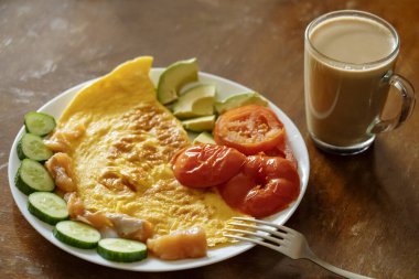 Omlet, domates, salatalık, avokado salatası ve kahve ile kahvaltı.