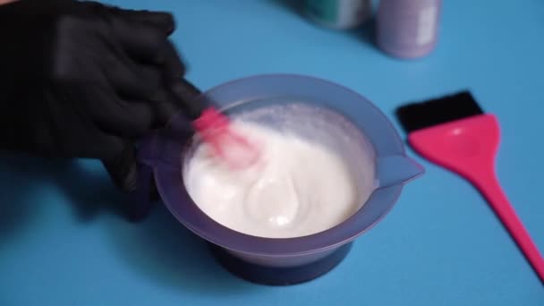 Les mains en gants noirs mélangent la teinture capillaire dans un bol. Préparation à la peinture capillaire — Video