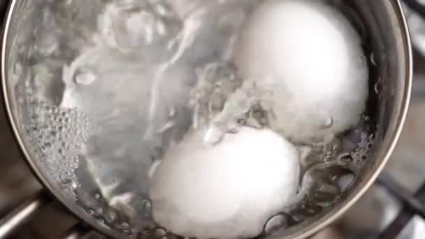 Två vita ägg kokas i en kastrull. Långsamma rörelser. — Stockvideo