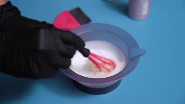 Handen in zwarte handschoenen roeren haarverf in een kom. Voorbereiding voor het schilderen van haar — Stockvideo