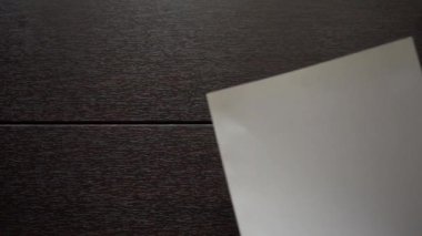 Tahta bir masanın üzerine boş bir kağıt parçası konur..