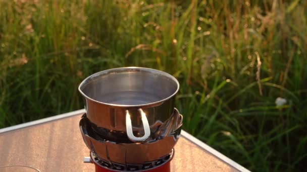 Hay vapor sobre un recipiente de agua parado en una estufa de gas en el camping. — Vídeos de Stock