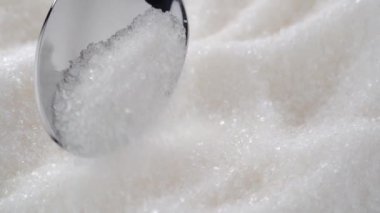 Beyaz şeker döner ve küçük bir metal kaşıktan düşer.